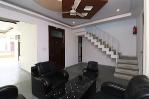 A room with a ceiling fan, a staircase, and two leather chairs. - Hotel O Krishna Inn (Lucknow)
