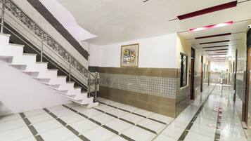 Un couloir d'hôtel avec un escalier, un mur orné de motifs et une œuvre d'art encadrée.