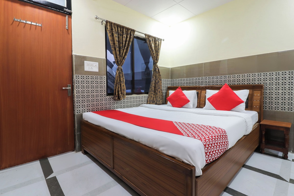 Una habitación de hotel con una cama de madera, una mesita de noche, un ventanal con cortinas y una puerta con cerradura.