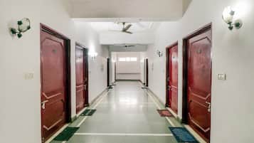 A hotel corridor with red doors, a ceiling fan, and a light fixture on the wall.
