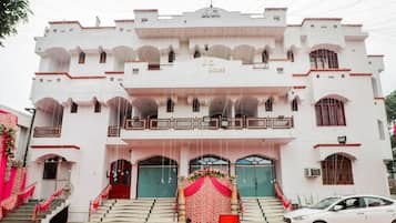 A white building with multiple balconies and a central entrance with a red carpet.