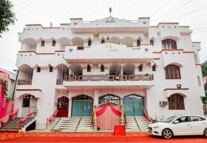 A white building with multiple balconies and a central entrance with a red carpet. - Hotel O Jc Guest House (Lucknow)