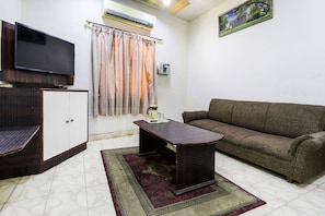 A living room with a sofa, a coffee table, a TV, and a cabinet. - Hotel O by OYO Surya (Ludhiana)