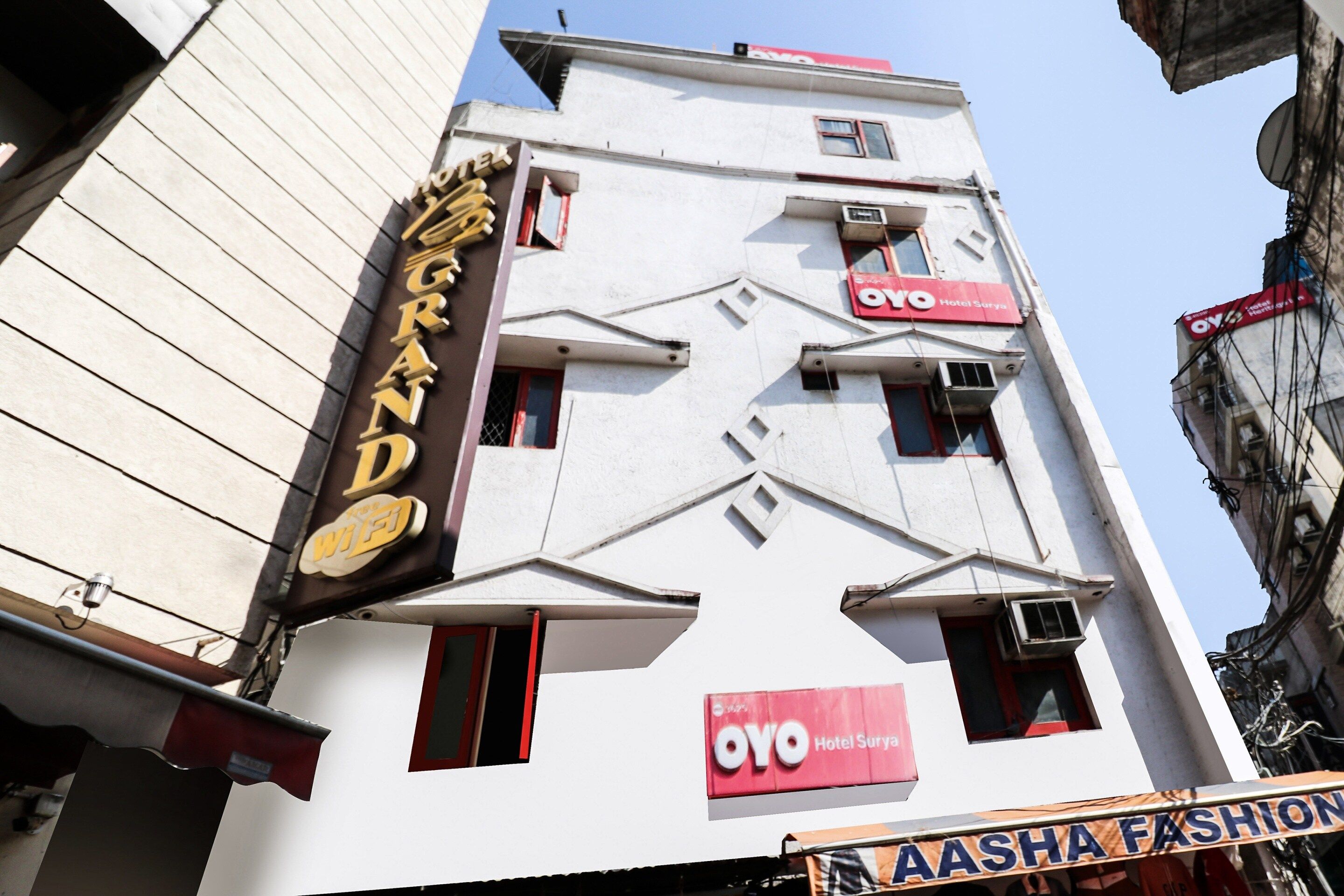 Um edifício com uma placa que indica 'Grand' e 'Aasha Fashion' no andar térreo.