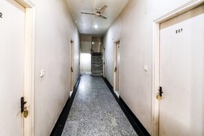 Un passadís amb un ventilador al sostre, una escala al final i portes numerades amb el 207.