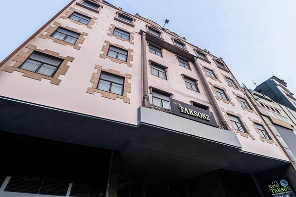 A multi-story building with a prominent sign for 'Hotel Takson' on the facade. - Townhouse Hotel Taksonz (Ludhiana)