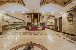 A spacious lobby with a central reception desk, a Buddha statue, and a marble floor with geometric patterns. - Townhouse Hotel Taksonz (Ludhiana)