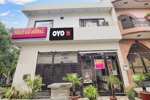 A hotel with a prominent sign for 'Prayag Hotel' and 'OYO' branding, a gated entrance, and potted plants in the foreground. - Hotel O by OYO Prayag Hotel (Ludhiana)