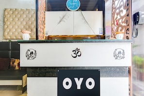 A reception desk with a sign reading 'OYO' and decorative elements including a Buddha statue, a bird motif, and a 'Pay Here' machine. - Hotel O by OYO Prayag Hotel (Ludhiana)