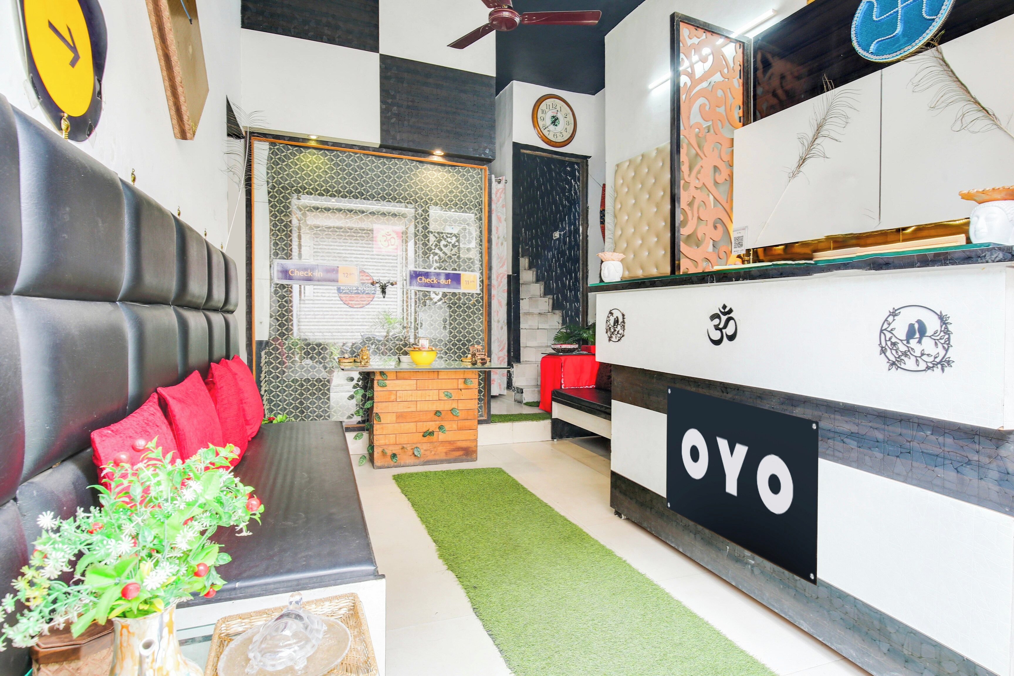 A modern interior with a check-in counter, a sofa with red cushions, and a decorative plant.