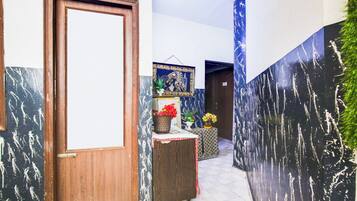 Um corredor com porta de madeira, parede com padrão em preto e branco e faixa azul.