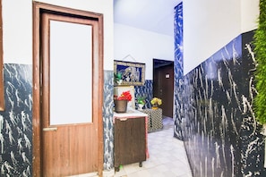 A hallway with a wooden door, a wall with a black and white pattern, and a blue banner. - Hotel O by OYO Prayag Hotel (Ludhiana)