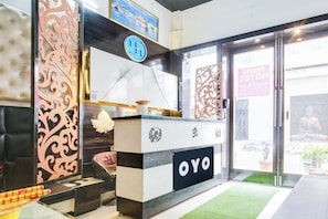 A reception desk with a logo, a sign with a symbol, and a door with a sign. - Hotel O by OYO Prayag Hotel (Ludhiana)