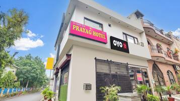 A hotel named 'Prayag Hotel' with a modern facade, a prominent sign, and a gated entrance.