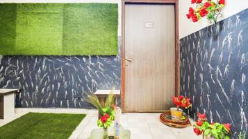 Quarto com área de grama sintética verde, porta numerada e parede com padrão preto.