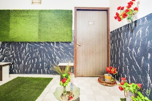A room with a green artificial grass area, a door with a number, and a wall with a black pattern. - Hotel O by OYO Prayag Hotel (Ludhiana)