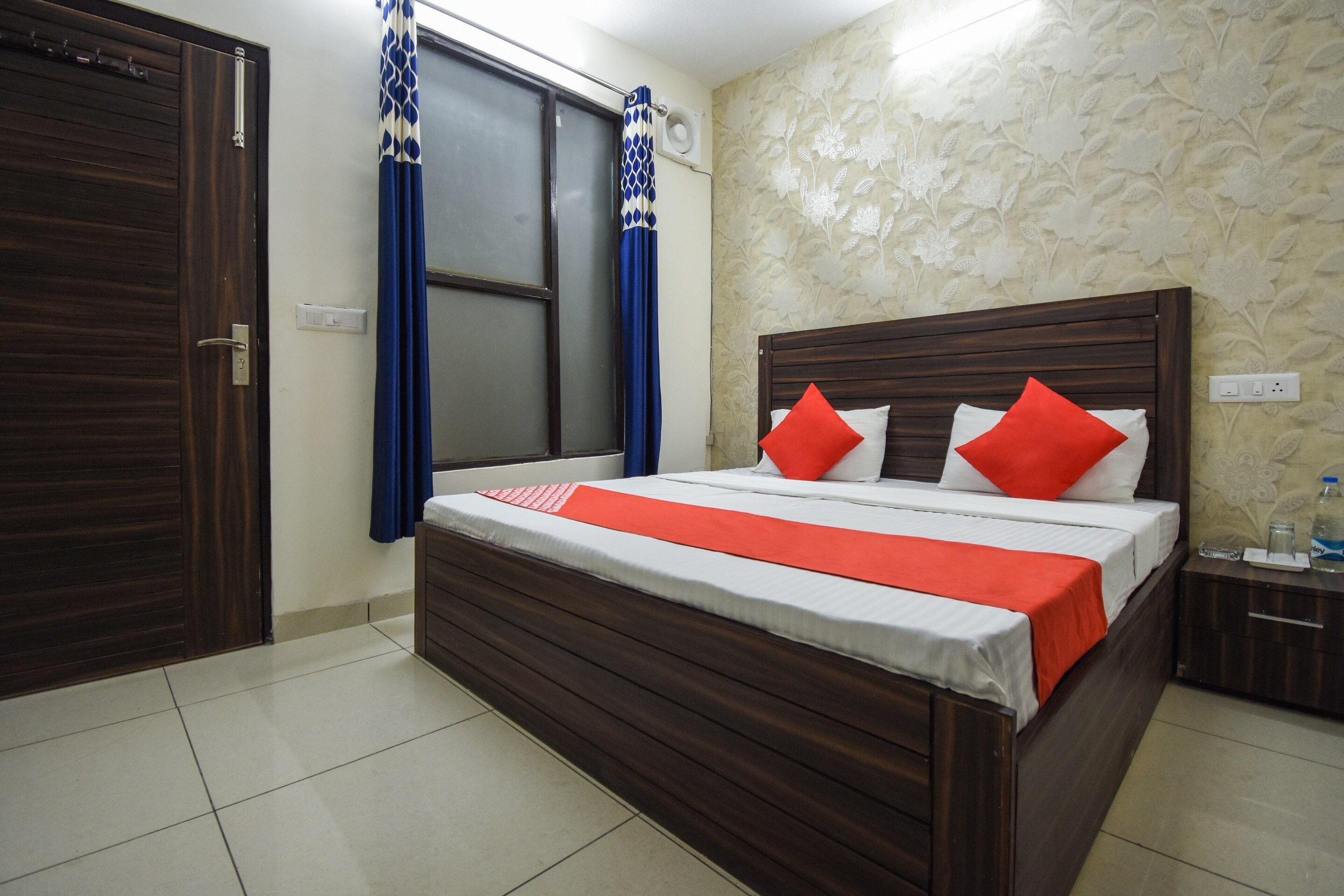 A hotel room with a wooden bed, a nightstand, a water bottle, and a window with curtains.