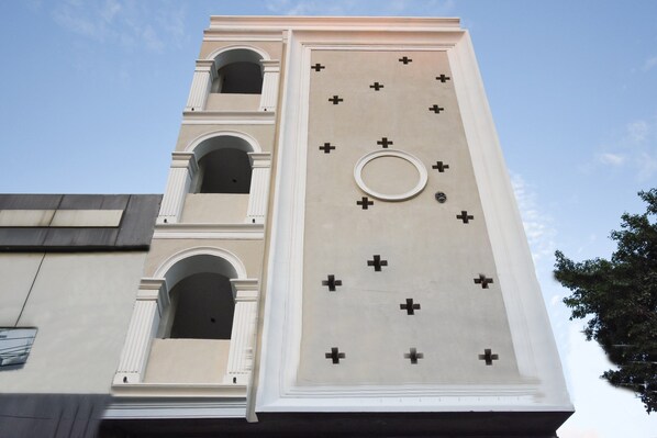 A building with a tall tower featuring arched windows and a series of crosses on its facade. - HOTEL O G S HOME (Ludhiana)