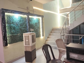 A staircase with a handrail, a wall-mounted air conditioner, and a chair. - Hotel O Capital Inn (Lucknow)