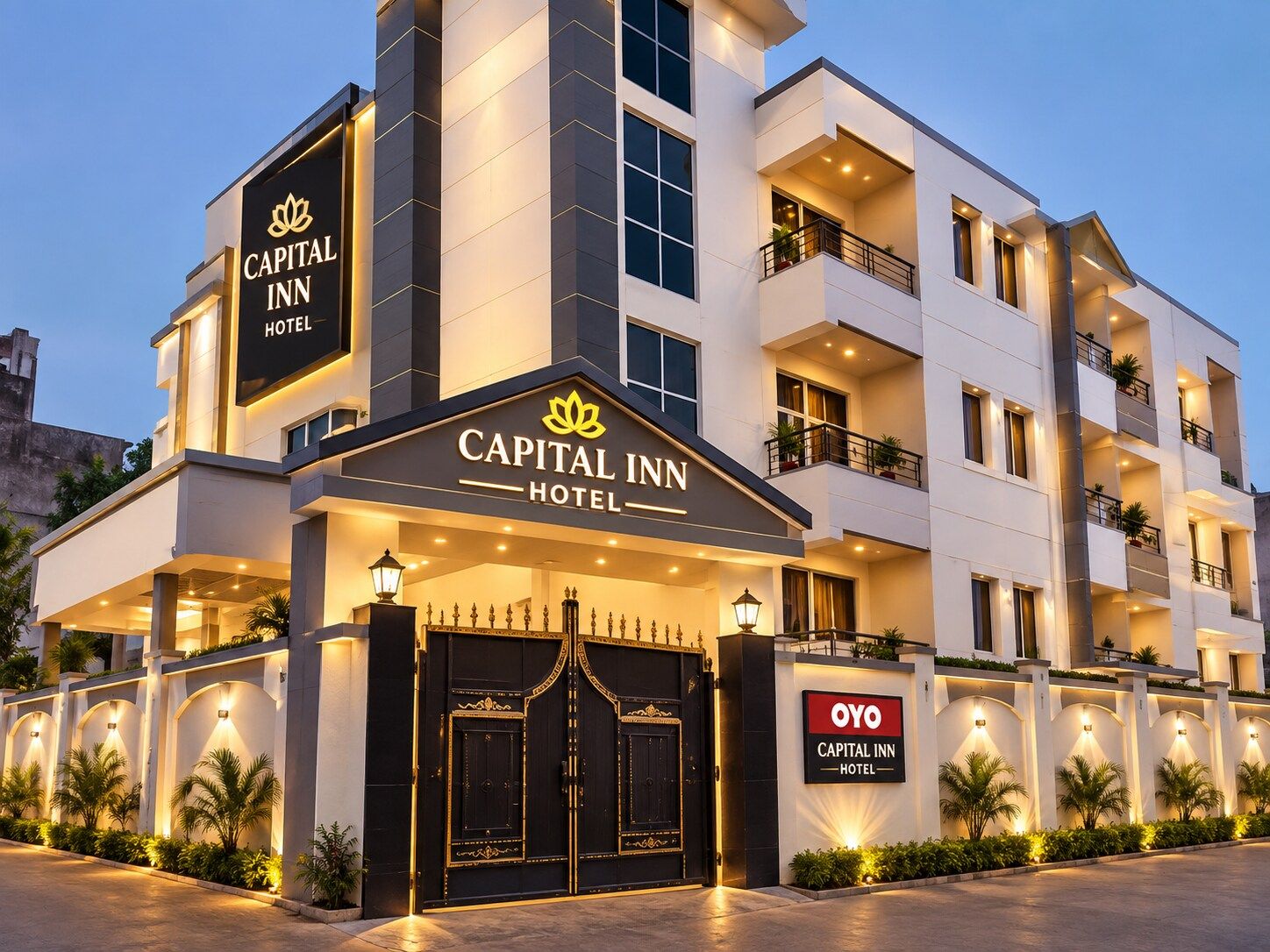 A multi-story hotel with a prominent entrance featuring a black gate and illuminated signage.