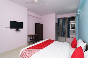 A bedroom with a bed, a desk, a chair, a wardrobe, a television, and a window with curtains. - Hotel O Capital Inn (Lucknow)