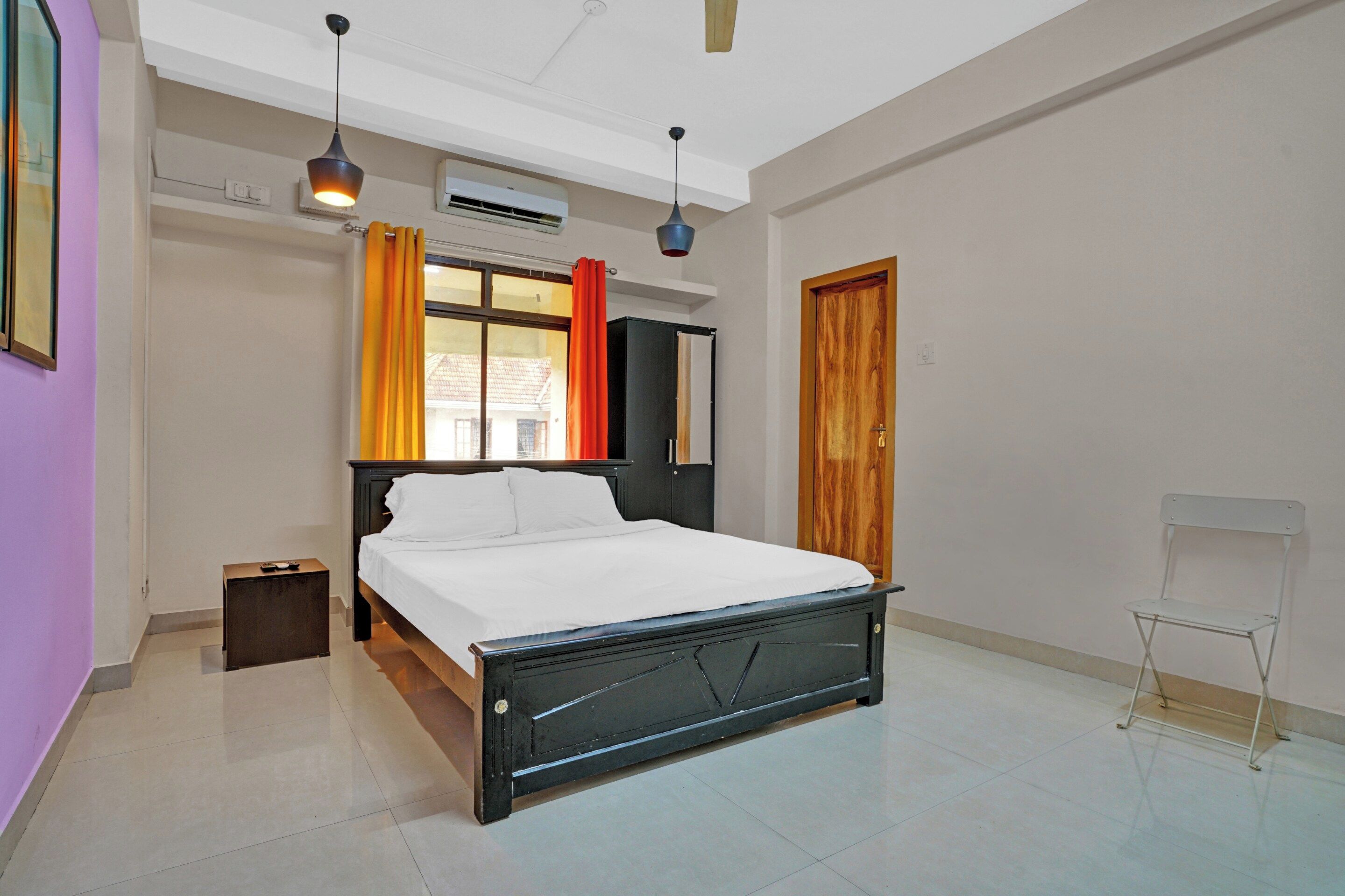 A bedroom with a bed, a nightstand, a wardrobe, a window with curtains, and a ceiling fan.