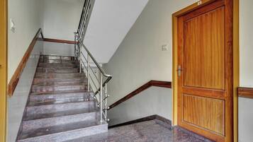 Un escalier avec une rampe métallique, une porte en bois et un sol carrelé.
