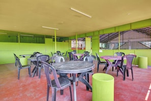 A dining area with round tables and chairs, green walls, and a high ceiling. - Collection O Lala Homes (Kochi)