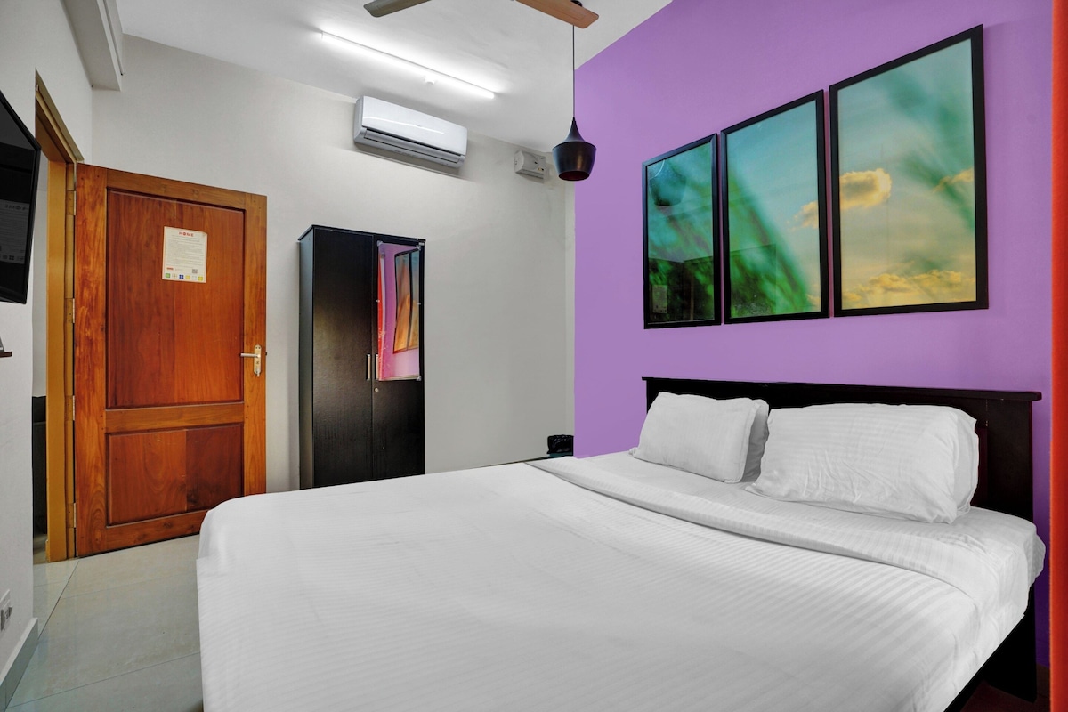 A bedroom with a bed, a wardrobe, an air conditioning unit, and a door.