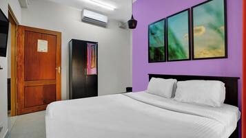 A bedroom with a bed, a wardrobe, an air conditioning unit, and a door.
