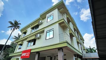 A multi-story building with balconies and air conditioning units, featuring a prominent red sign for OYO Flagship Lala Homes.