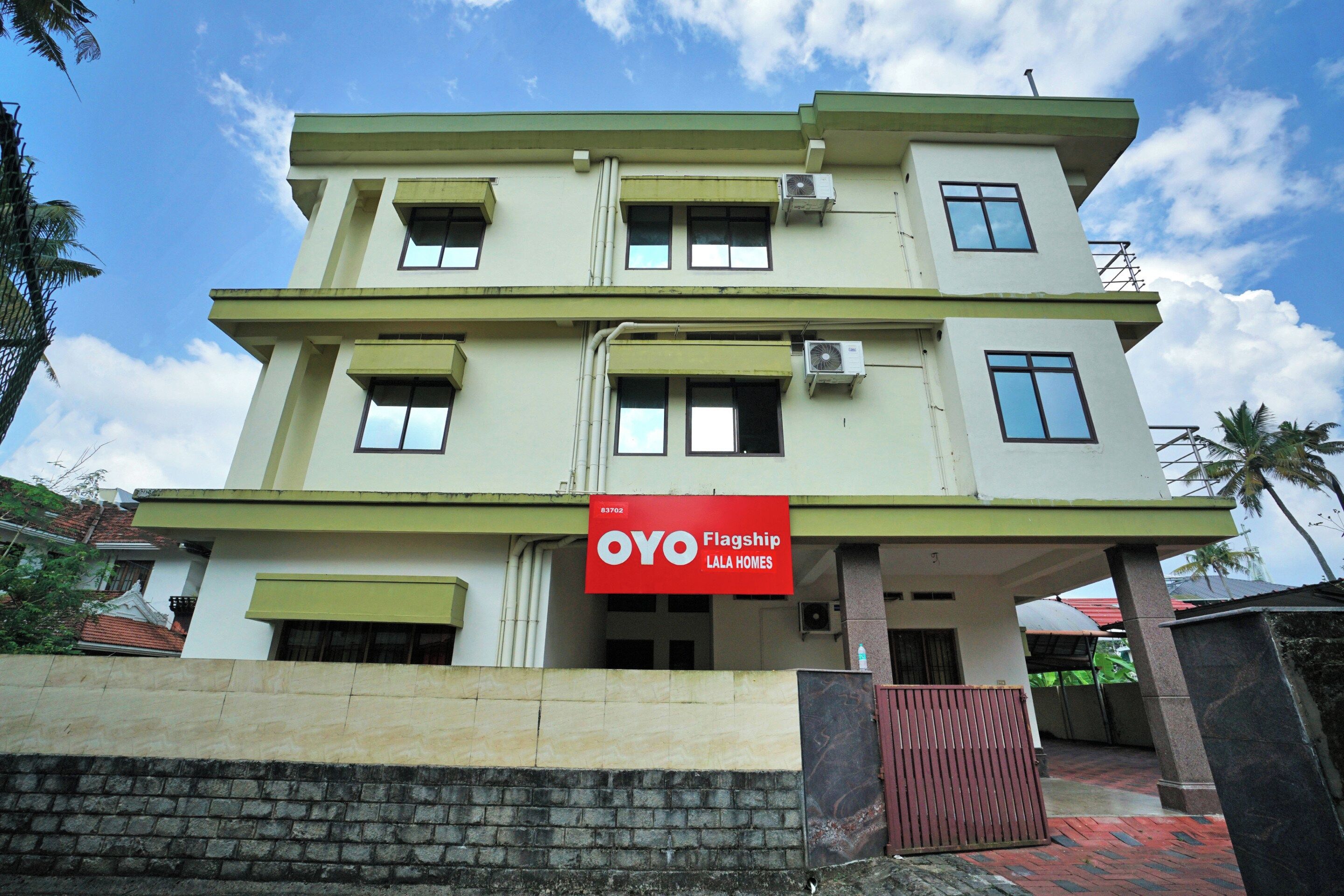 A multi-story building with a flat roof, multiple windows, and an air conditioning unit.