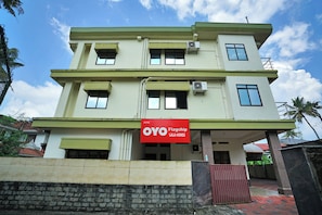 A multi-story building with a flat roof, multiple windows, and an air conditioning unit. - Collection O Lala Homes (Kochi)