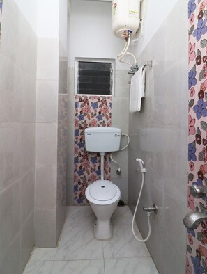 A small bathroom with a toilet, a shower, and a wall-mounted heater.