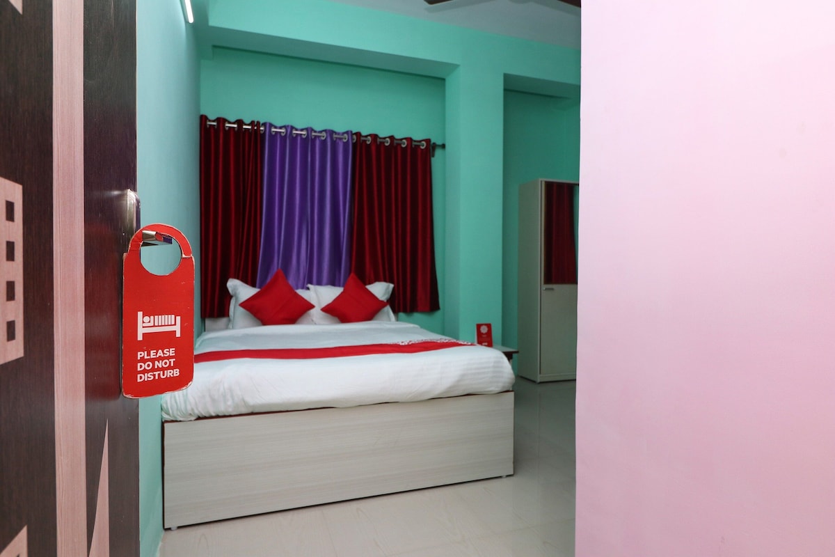 Una camera d'albergo con un letto, tende rosse e un cartello rosso appeso al muro.