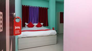 Una camera d'albergo con un letto, tende rosse e un cartello rosso appeso al muro.