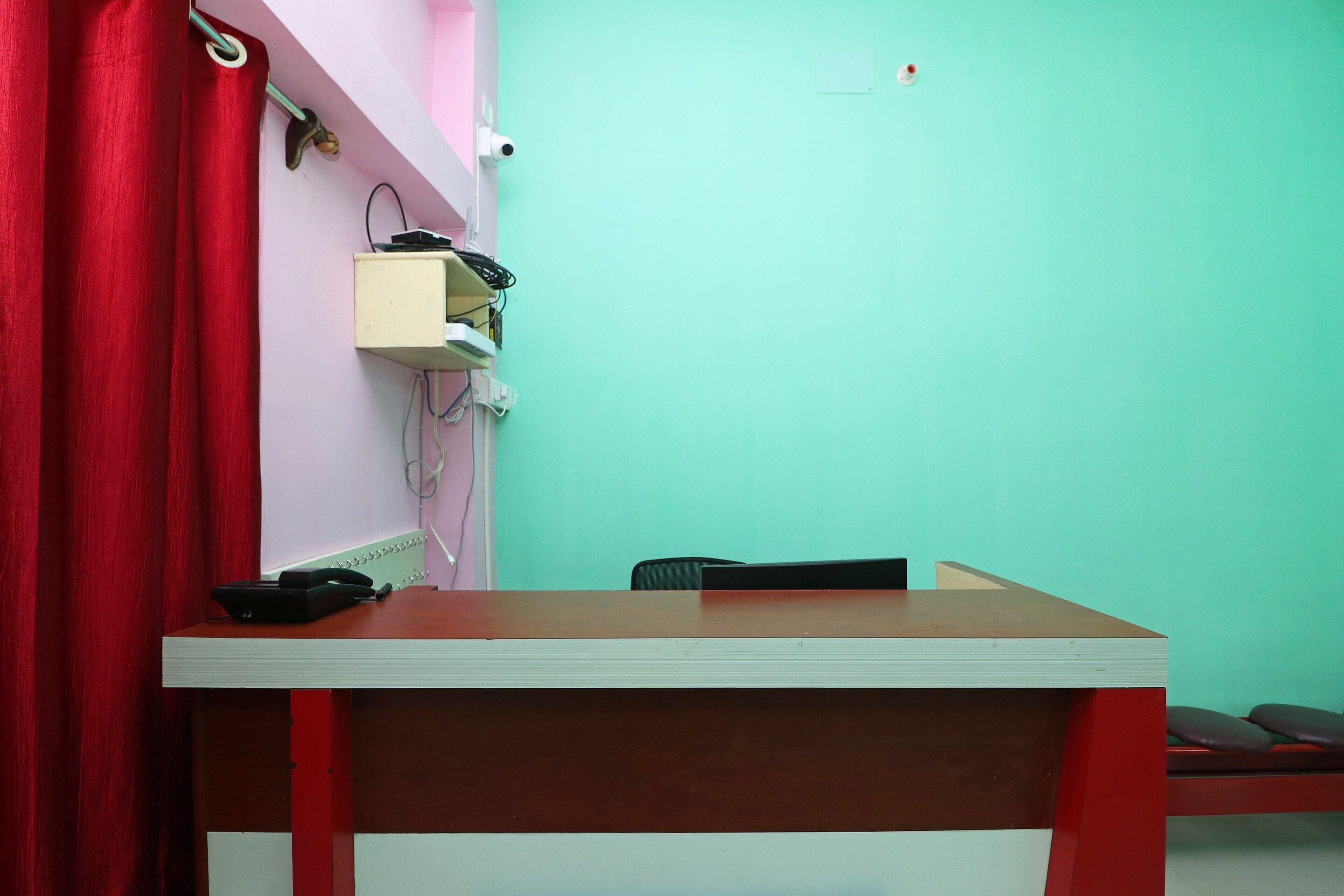 Una habitación con escritorio, silla y una cortina roja.