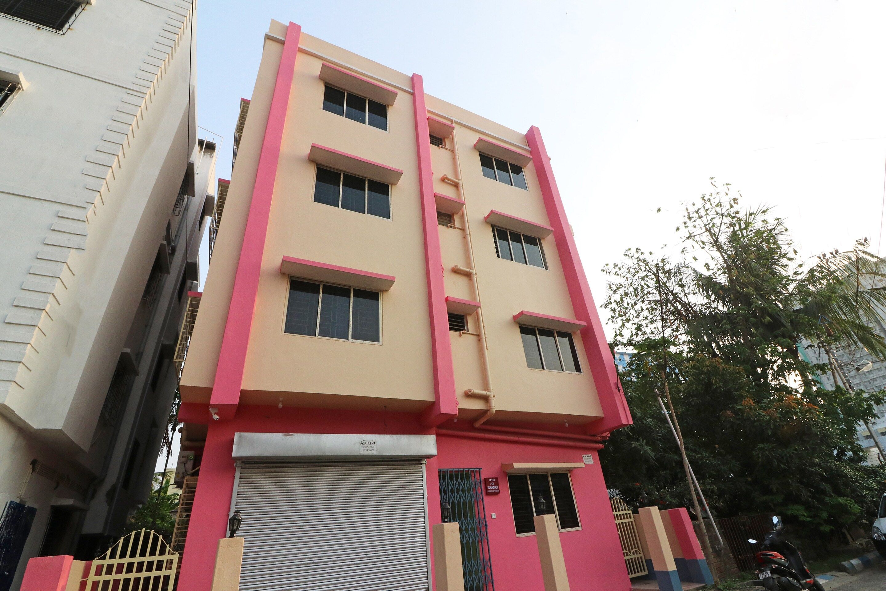 A multi-story building with a flat facade, a closed shutter at the ground level, and a gated entrance.
