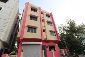 A multi-story building with a flat facade, a closed shutter at the ground level, and a gated entrance.