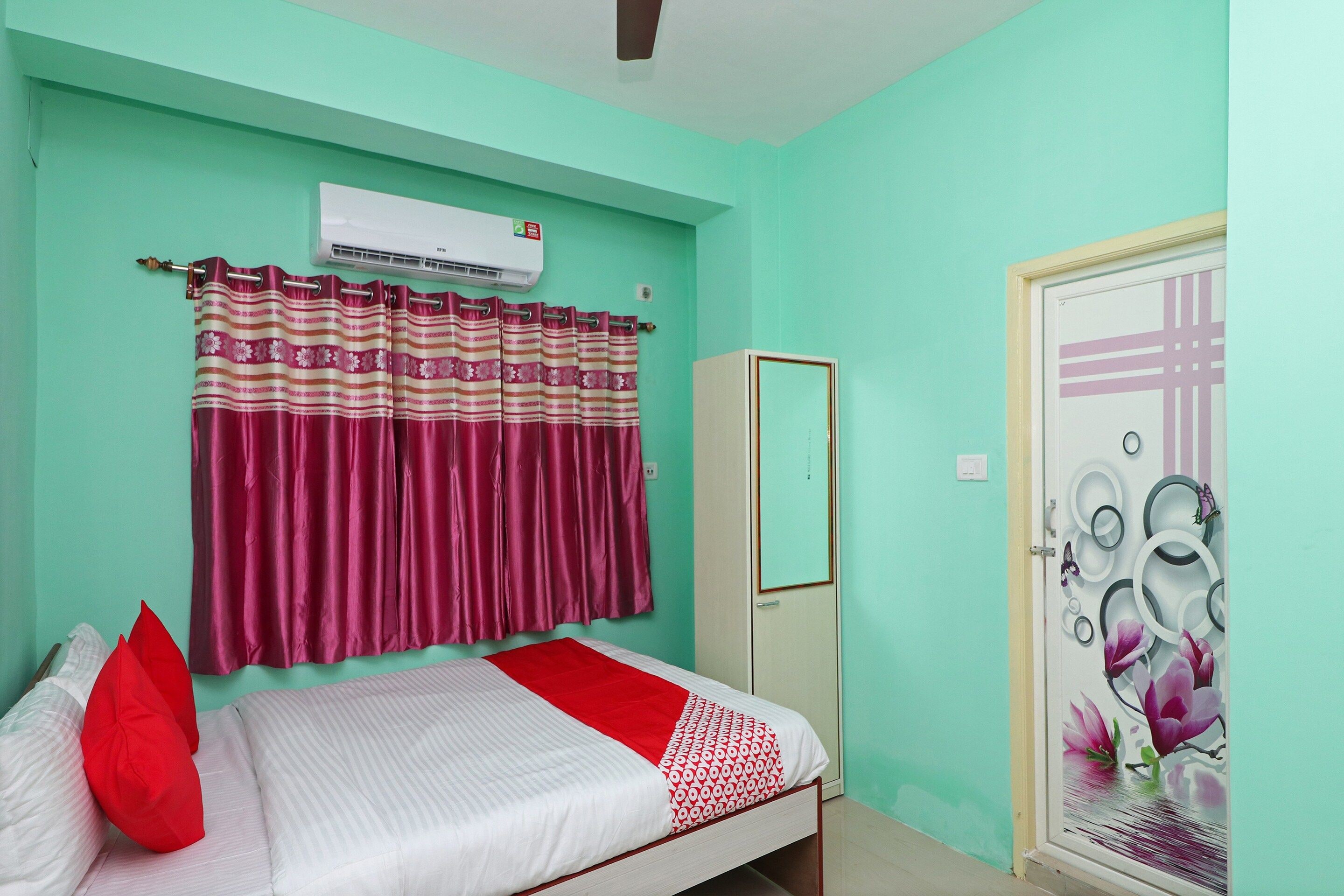 A room with a bed, a wardrobe, a door with a decorative plate, and an air conditioning unit.