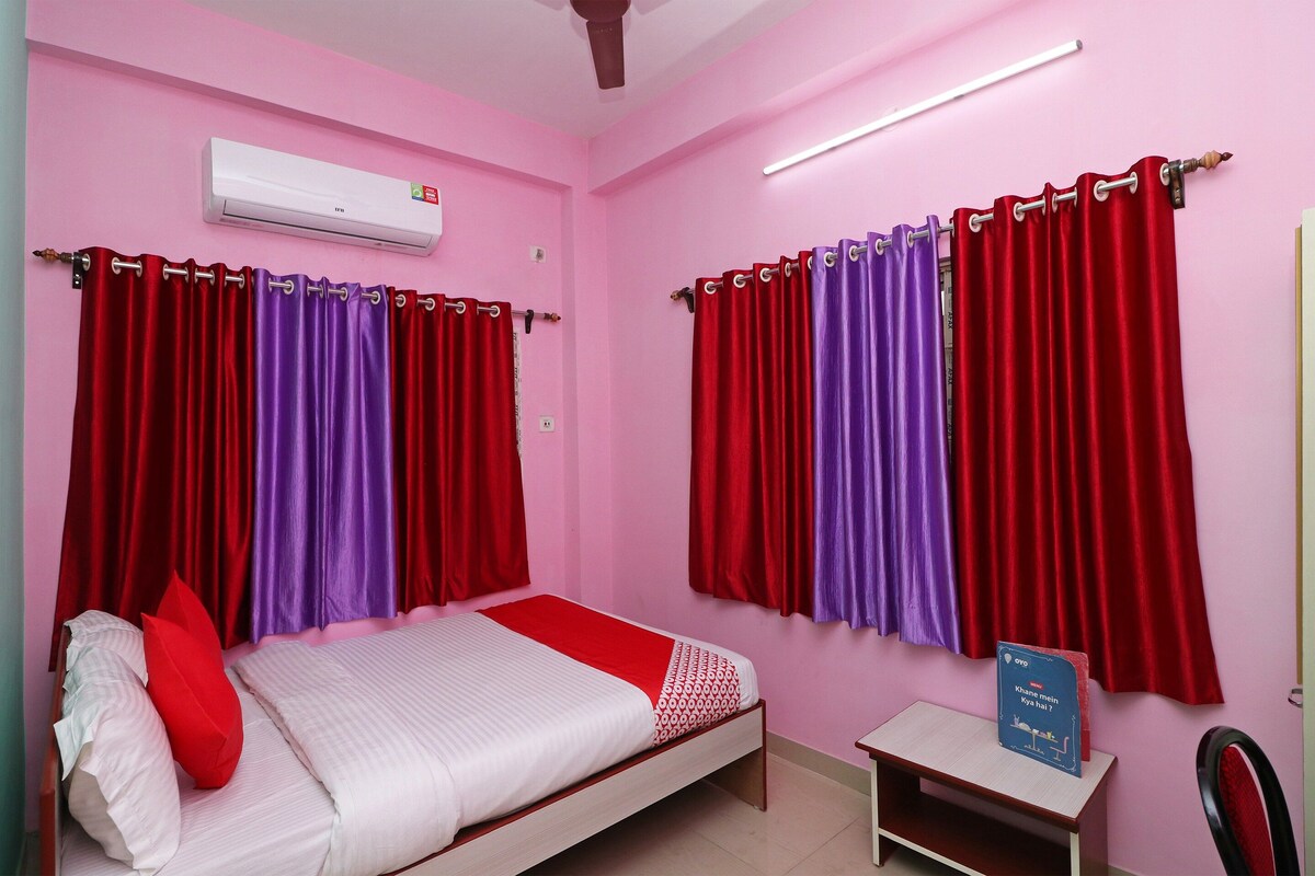 A bedroom with a bed, a nightstand, a small table, and curtains.