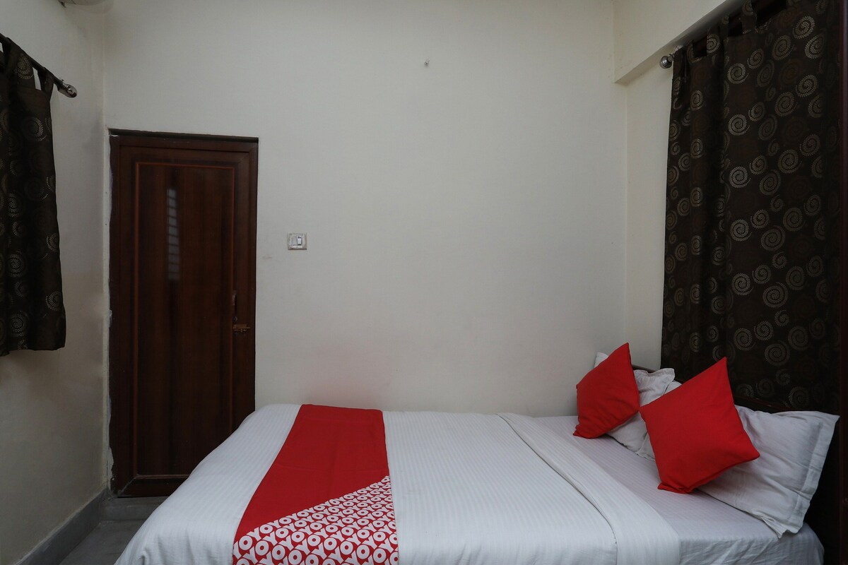 A bedroom with a bed, a door, and a patterned curtain.