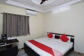 A hotel room with a bed, a desk, a chair, an air conditioner, and a ceiling fan. - Hotel O Raviz Inn (Kolkata)