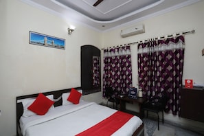 A hotel room with a bed, a desk, a chair, an air conditioning unit, and a curtain. - Hotel O Raviz Inn (Kolkata)