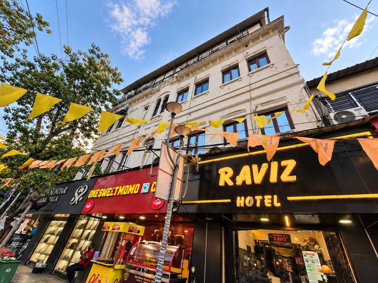 A hotel named RAVIZ with a modern facade, large windows, and a visible entrance.