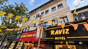 A hotel named RAVIZ with a modern facade, large windows, and a visible entrance.