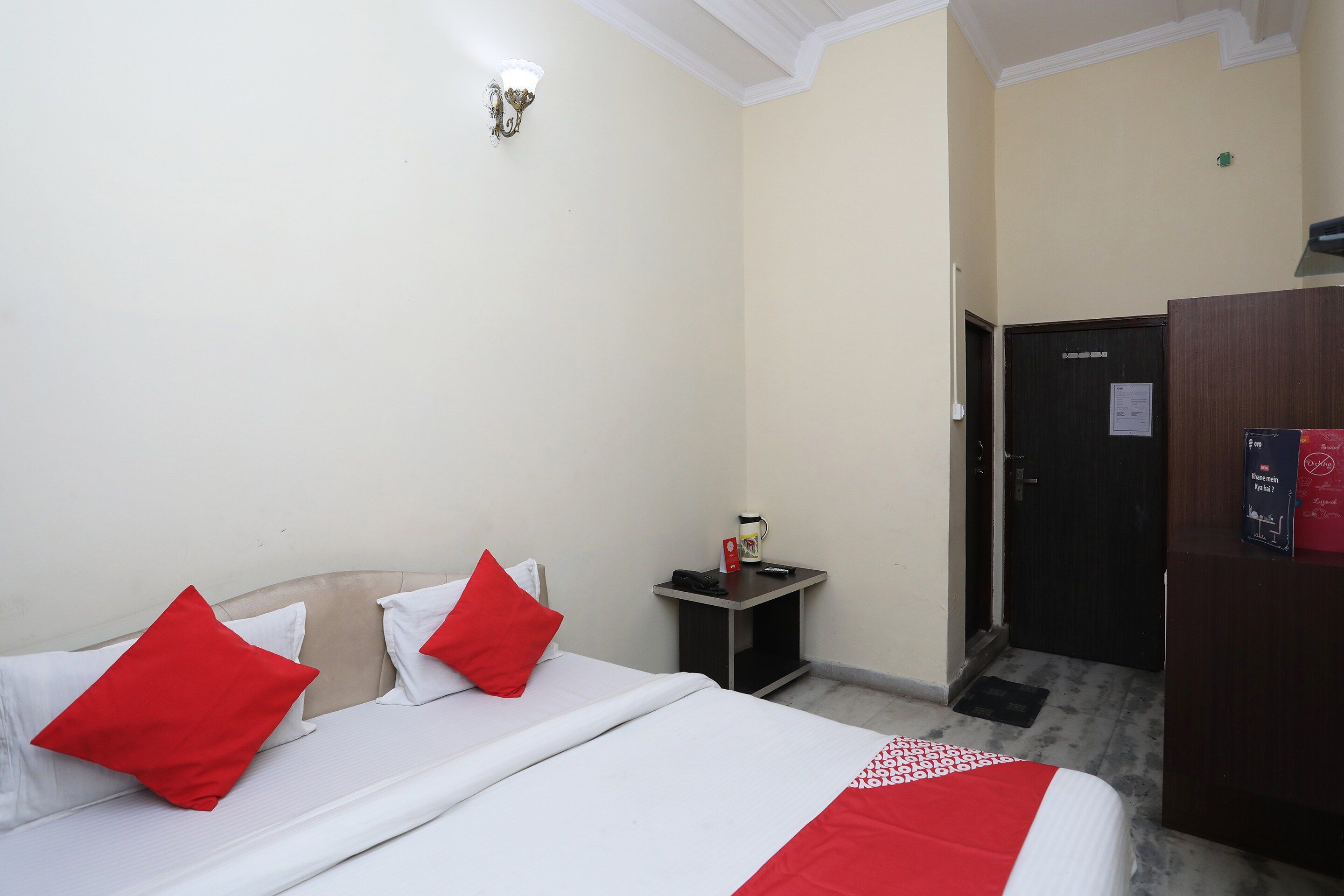 A hotel room with a bed, a bedside table, a wardrobe, and a door.