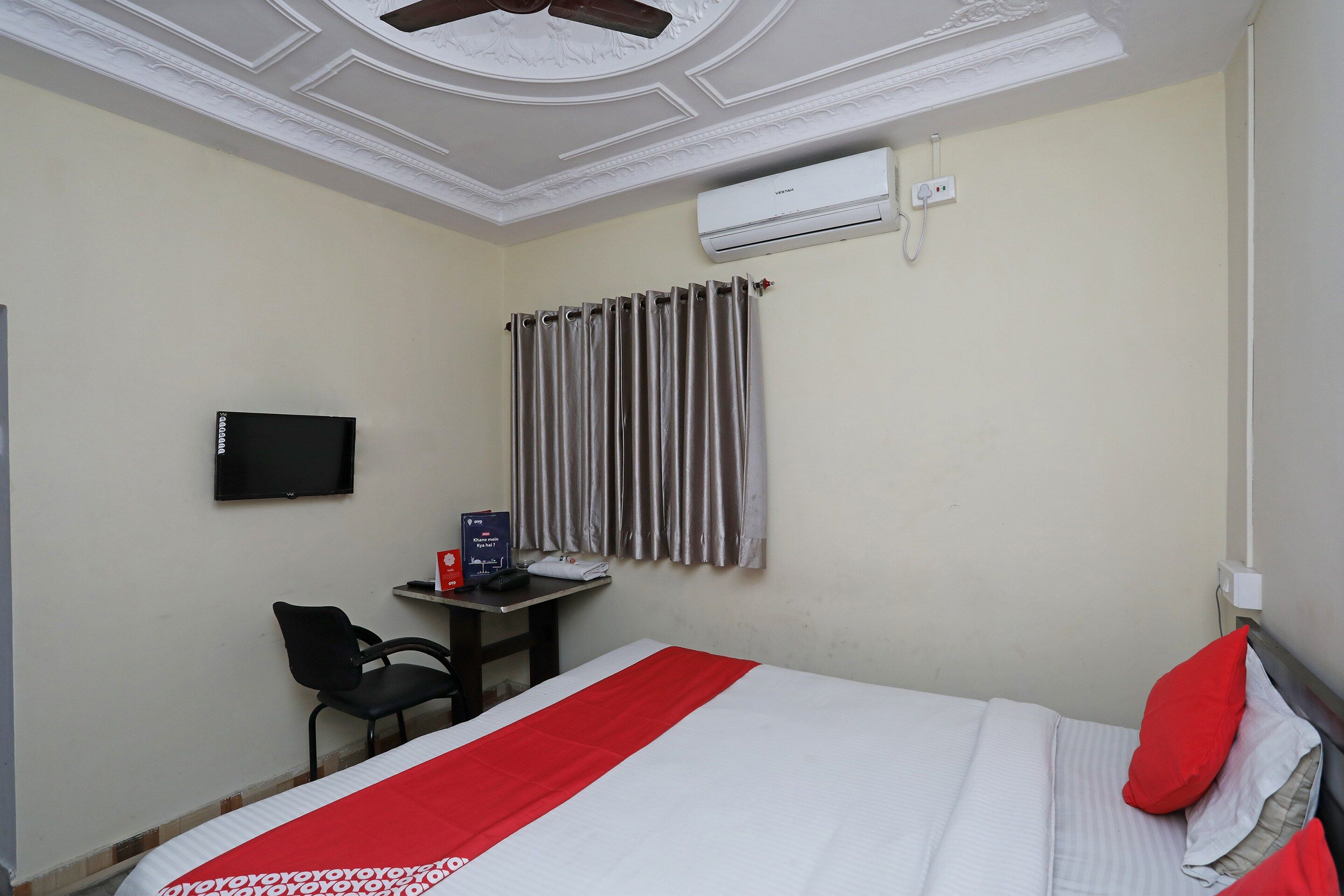 Une chambre d’hôtel équipée d’un lit, d’un bureau, d’une chaise, d’un climatiseur et d’un téléviseur.