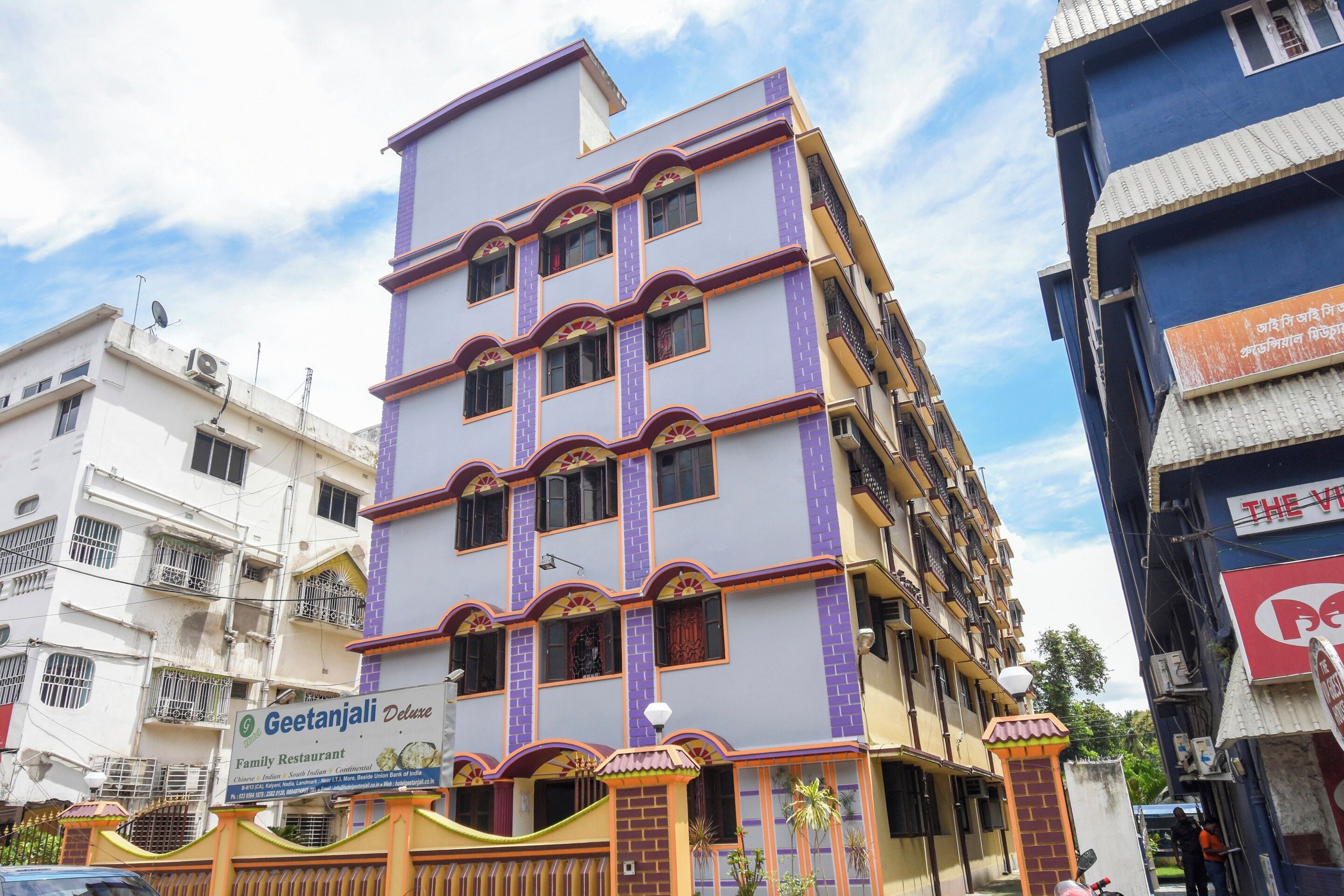 Un edificio de varios pisos con un cartel que anuncia Geetanjali Deluxe Family Restaurant.