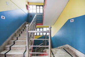 A staircase with metal railings and marble steps, leading to a landing with a window.